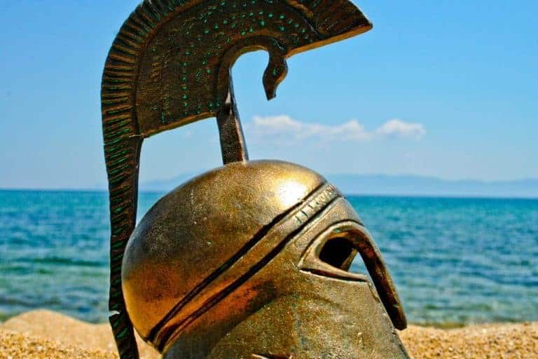 Шлем древнего героя на песке на фоне моря